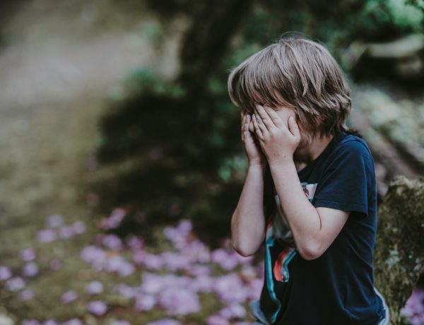 boy covering his face while standing